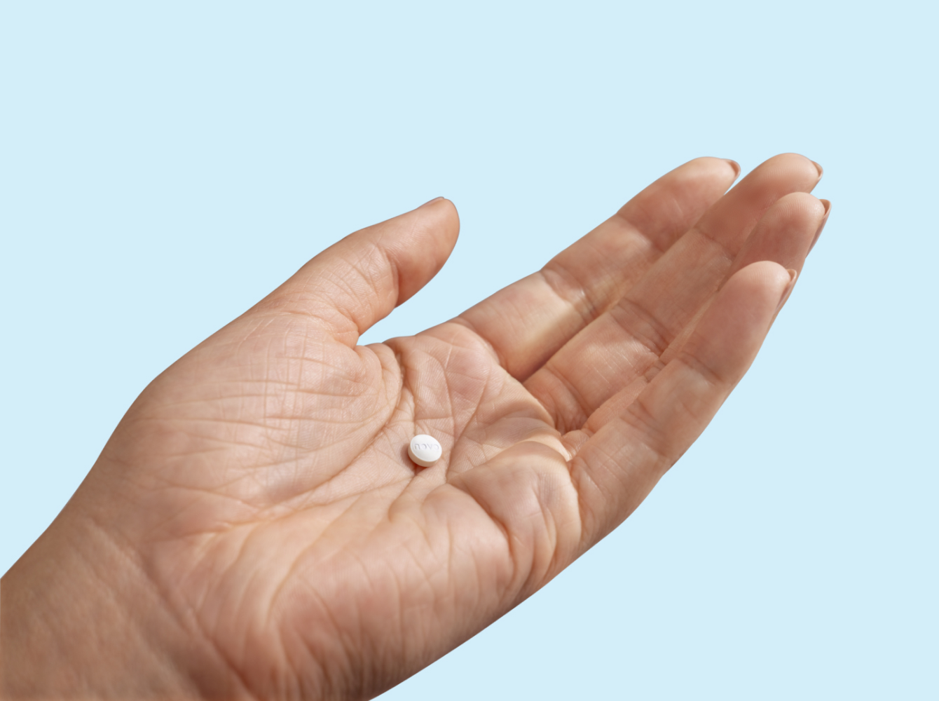 Hand holding a small white pill