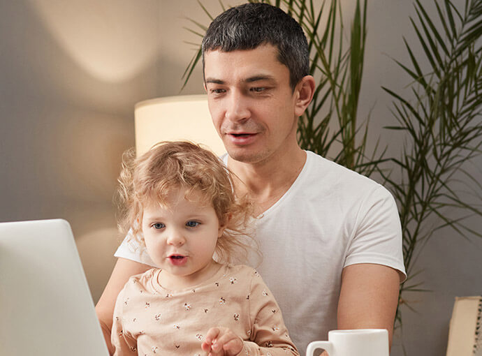 Father and daughter smiling looking at a computer.