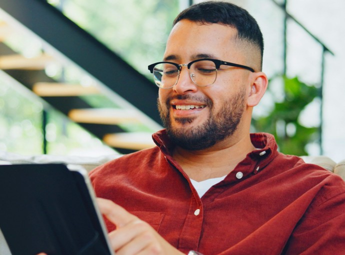 Man smiling at his phone while holding a mug